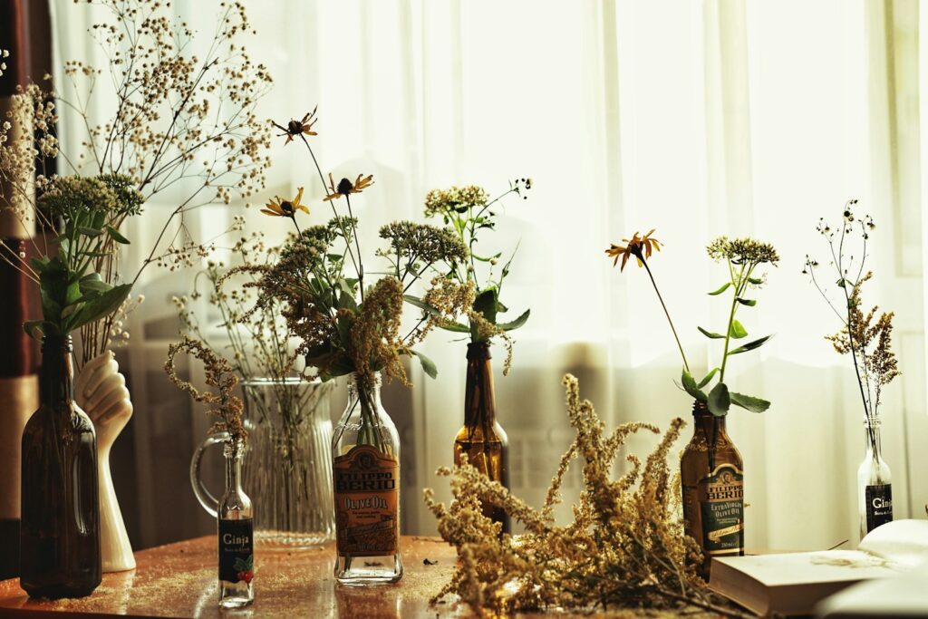 clear glass bottle beside white flowers in clear glass vase