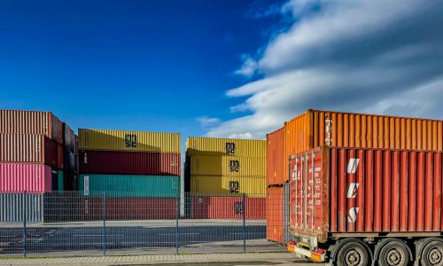 a truck is parked in front of a bunch of shipping containers