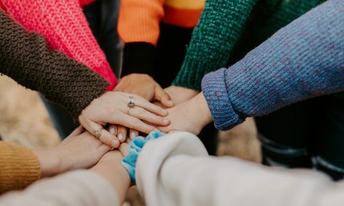 person in red sweater holding babys hand